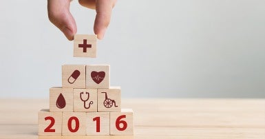 Hand arranging wood block stacking with icon healthcare medical and the year 2016