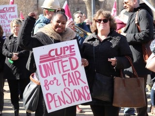 Two women at a CUPE 1975 rally, one holds a sign that says United for Fair Pensions