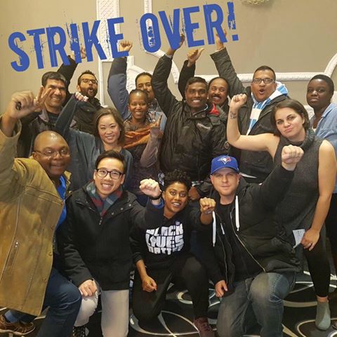 Group of people smiling with their fists raised, with blue text that says Strike Over!