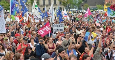 Large crowd of people carrying flags and posters at rally