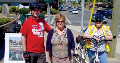 One man and two women stand with their bikes on a sunny day