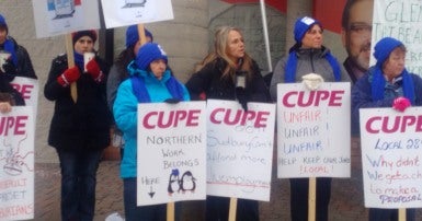 Group of women in winter clothing holding CUPE signs