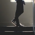 Back lit, person from the waist down standing on the landing of a stair well