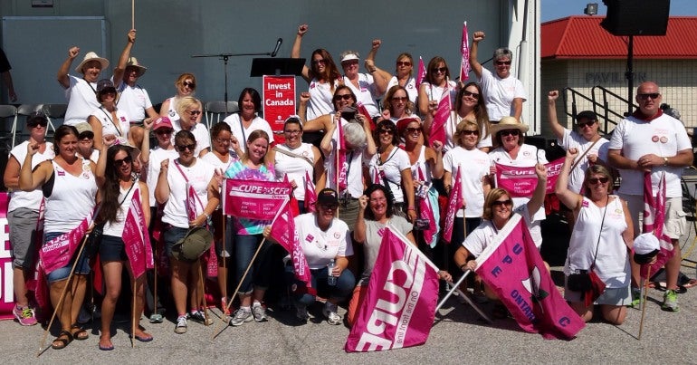Group of protesters with pink flags under an awning