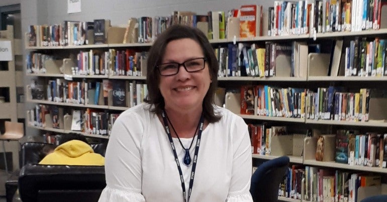 woman standing behind a table at a library 