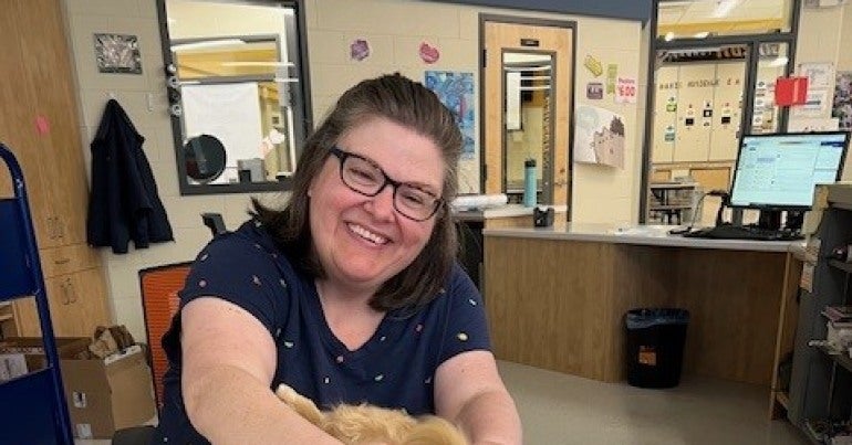 Woman sitting at a table petting a dog