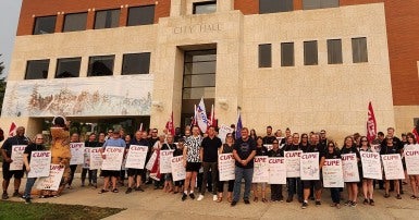 Workers with picket signs standing in front of City Hall