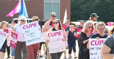 People holding signs protesting cuts to education