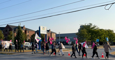 Workers walking a picket line with flags and signs