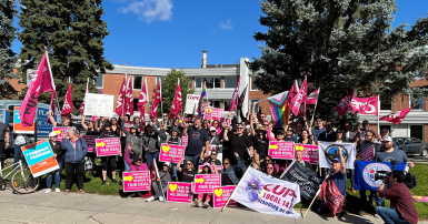 Workers pose for photo with flags and picket signs