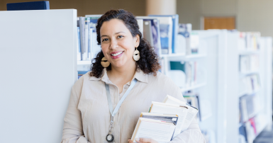 A woman poses in the library for her business headshot.