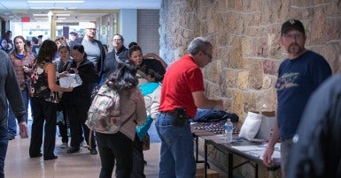 Large group in line in a hallway with some bent over a table with union materials on it