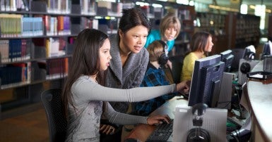 Librarian at a computer with young people