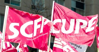 Two pink flags, one says SCFP, the other says CUPE