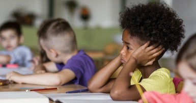 Young girl with her head in her hands at a school desk