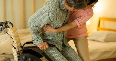 Personal support worker helps a man into his wheelchair