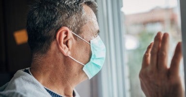 Man wearing mask staring out window