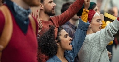 Group of people holding signs and chanting at a demonstration