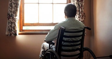 Elder man in a wheelchair looking out the window