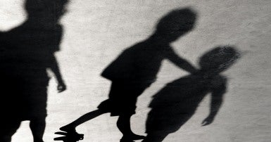 Shadows of three children on a grey concrete surface with cracks