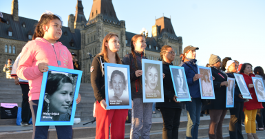 Indigenous girls hold up images of missing and murdered Indigenous women in front of Parliament