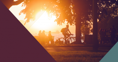 Cyclist and people gathered in a park by the beach at sunset