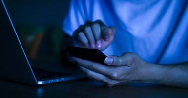 Person staring at a laptop in dim light