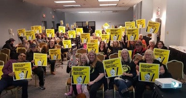 CUPE members in a meeting holding up signs