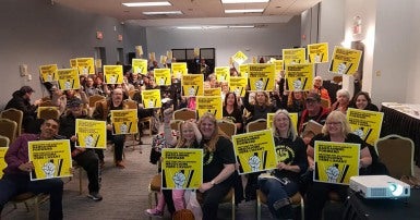 Les membres du SCFP lors d'une réunion en train de brandir des pancartes