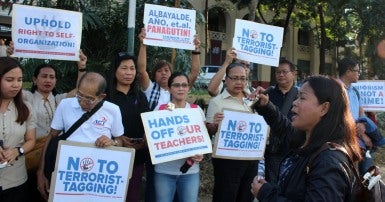 Alliance of Concerned Teachers rally in the Philippines with signs that  say "No to terrorist tagging"and "Hands off our teachers."