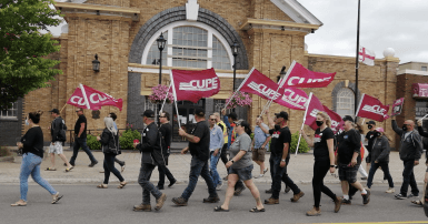 CUPE 1349 members carrying CUPE flags march in front of town hall in Grand Falls-Windsor NL