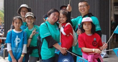 Group of adults and children smiling and holding flags