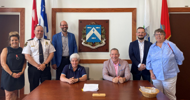 People sitting and standing at a table with a signed agreement