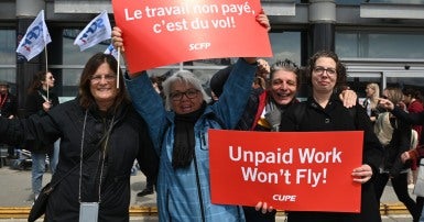 People holding flags and protest signs that say unpaid work won't fly