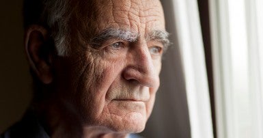 A retired man looks out the window
