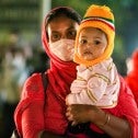 A garment worker on the way out of work with her child in Dhaka, Bangladesh.