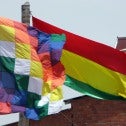 Image of checkered Indigenous flag and red, yellow and green Bolivian flag 