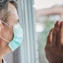 Man wearing mask staring out window