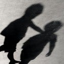 Shadows of three children on a grey concrete surface with cracks