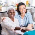 LGBTQ2+ seniors Woman using a wheelchair, next to a second woman, shaking hands with a third.