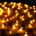 Many lit candles against a black background