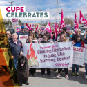 Group shot of workers holding CUPE signs supporting public libraries and big black dog