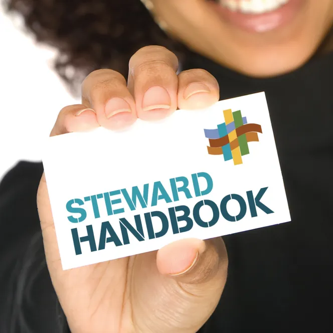 Person holding up card that says Steward Handbook