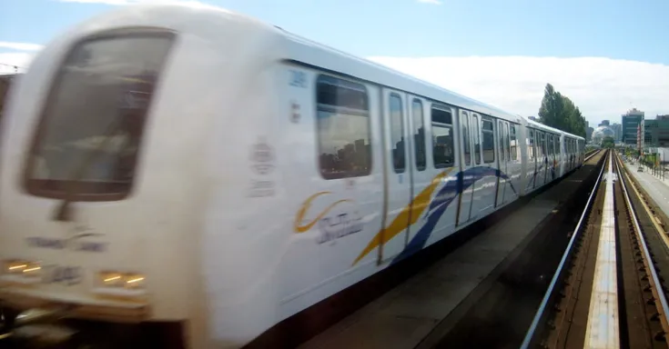 Image of Vancouver SkyTrain, elevated light rapid transit train and track with blue sky in the background.