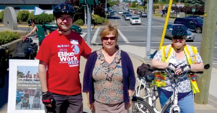 One man and two women stand with their bikes on a sunny day