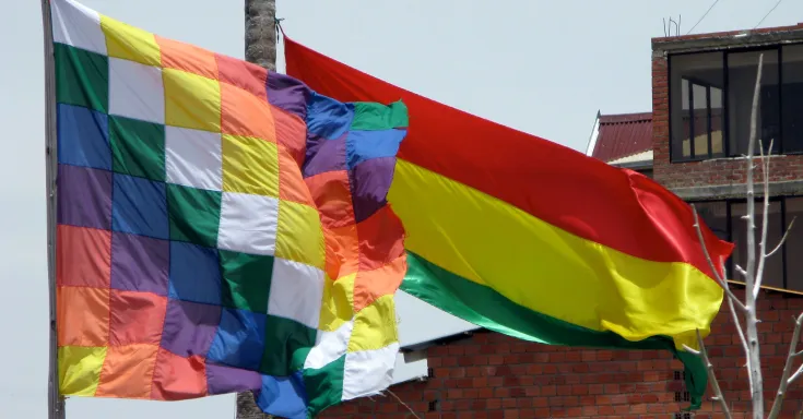 Image of checkered Indigenous flag and red, yellow and green Bolivian flag 