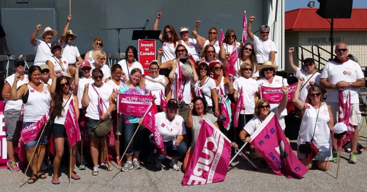 Group of protesters with pink flags under an awning