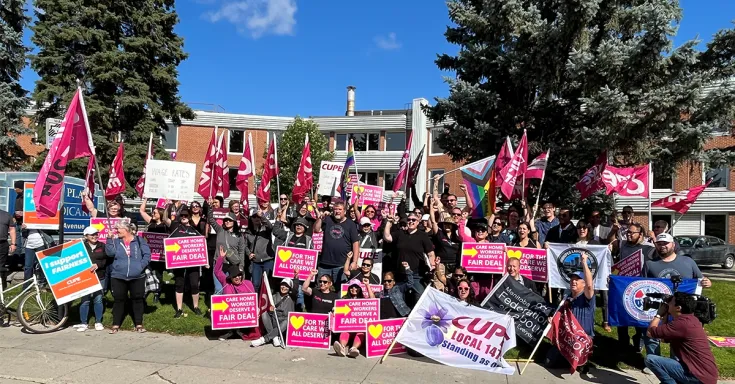 Workers pose for photo with flags and picket signs