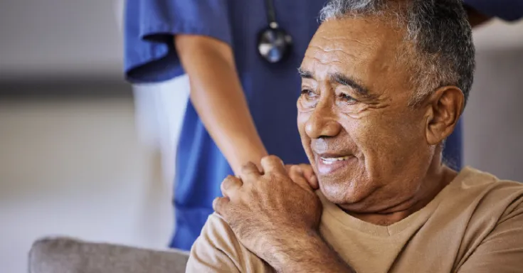 A health care workers places her hand on the shoulder of an elder