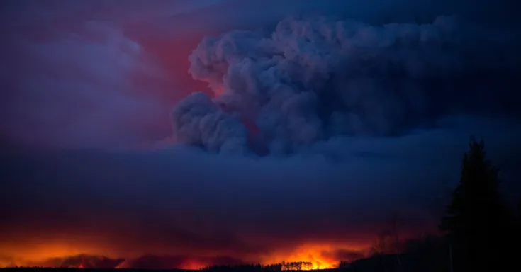 Dark cloud in night sky above wildfire